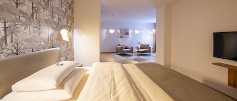 Una habitación de hotel con cama, televisión y zona de estar con mesa y sillas.