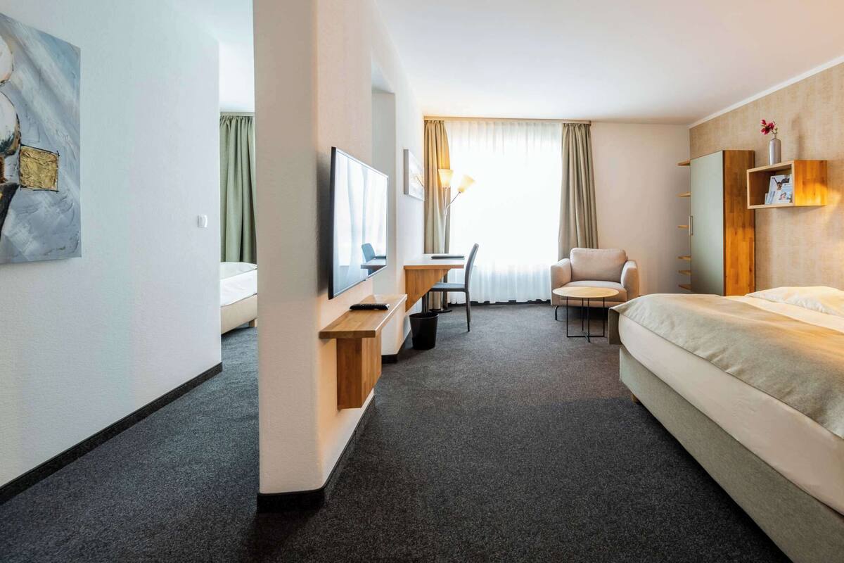 Ein Hotelzimmer mit einem Bett, einem Schreibtisch, einem Sessel, einem Fernseher und einer Lampe.
