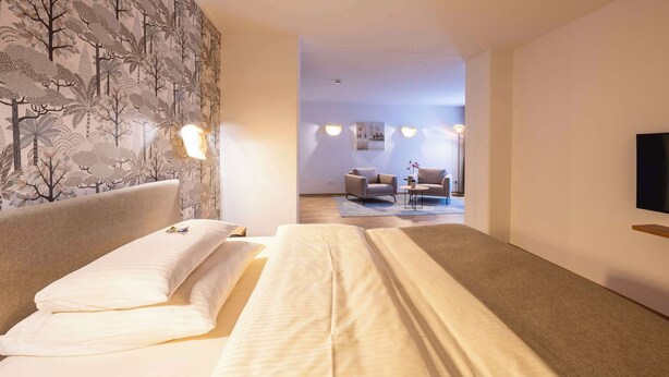 A hotel room with a bed, a TV, and a seating area with chairs and a table. - Best Western Plus iO Hotel (Schwalbach am Taunus)