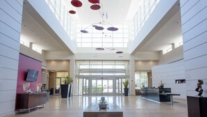 Eine geräumige Lobby mit hoher Decke, einer Rezeption und einer zentralen Sitzecke.