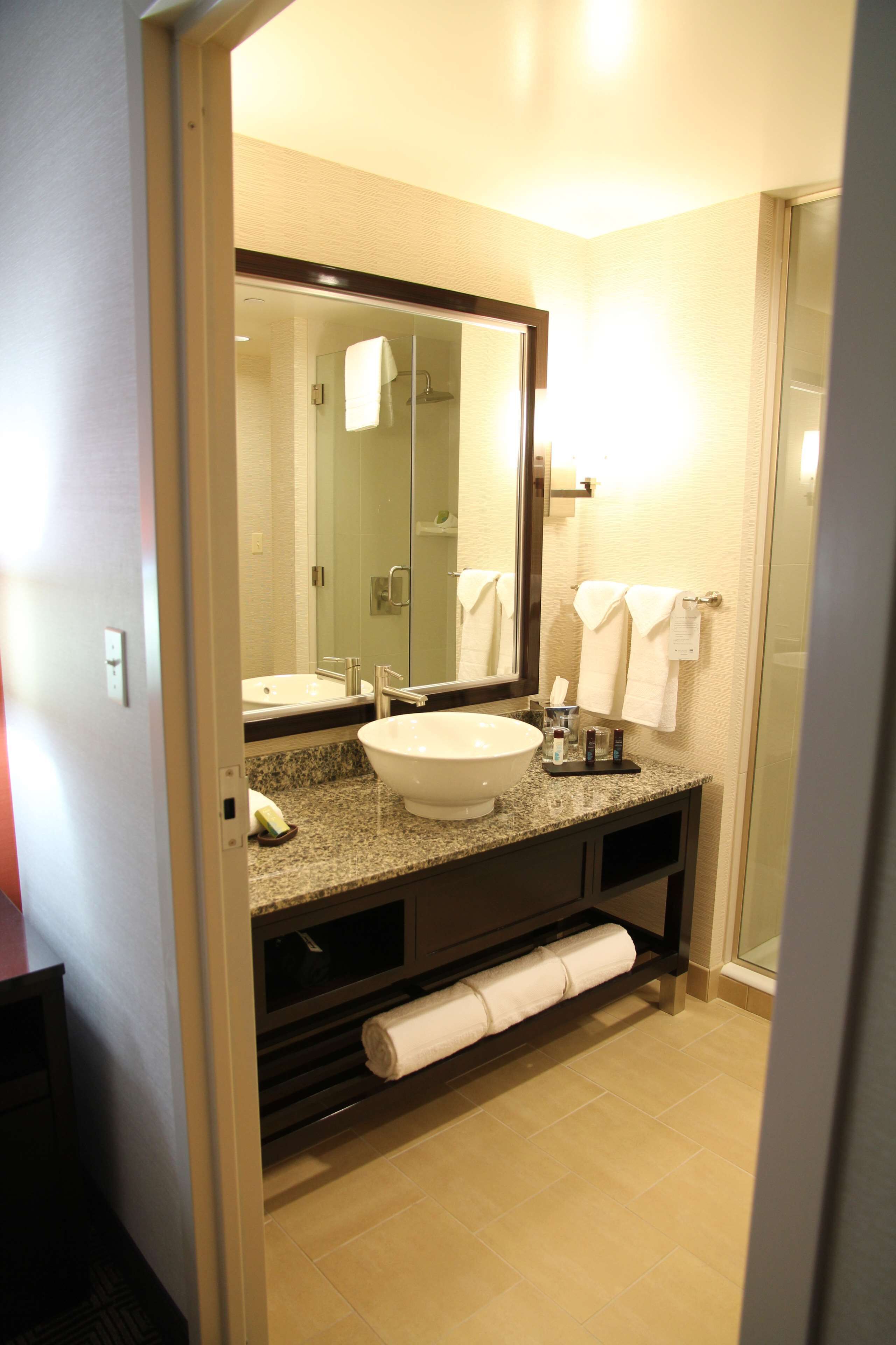 A modern bathroom with a large mirror, a sink, and a shower.
