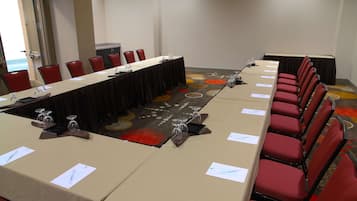 Un salón de conferencias con una larga mesa, sillas rojas y una alfombra con un diseño circular.