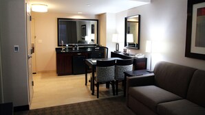 Ein Hotelzimmer mit einer Küchenzeile, einem Essbereich mit Stühlen, einem Sofa und einem großen Spiegel.