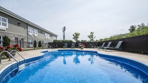 En swimmingpool med liggestole og en bygning i baggrunden.