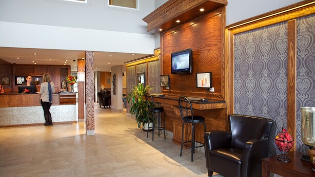 Et hotellobby med reception, barområde, siddepladser og et fjernsyn.