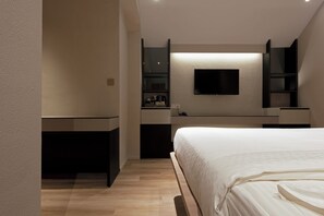Een moderne slaapkamer met een groot bed, een flatscreen televisie aan de muur en ingebouwde kasten.