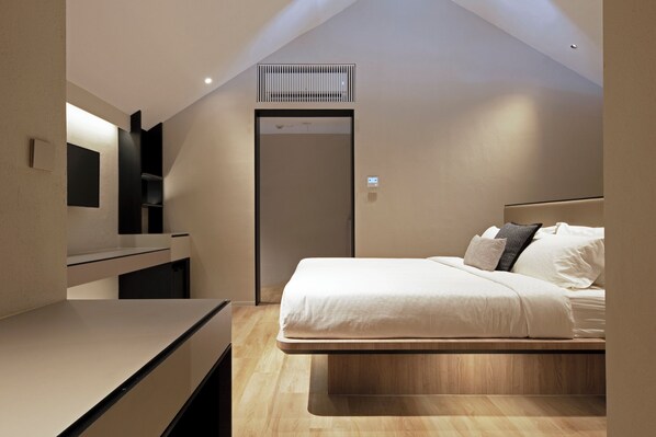 Een moderne slaapkamer met een bed, een inbouwkast en een kleine kast.