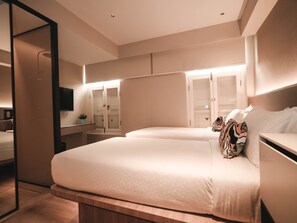 Een moderne hotelkamer met een groot bed, nachtkastje, spiegel en garderobe.