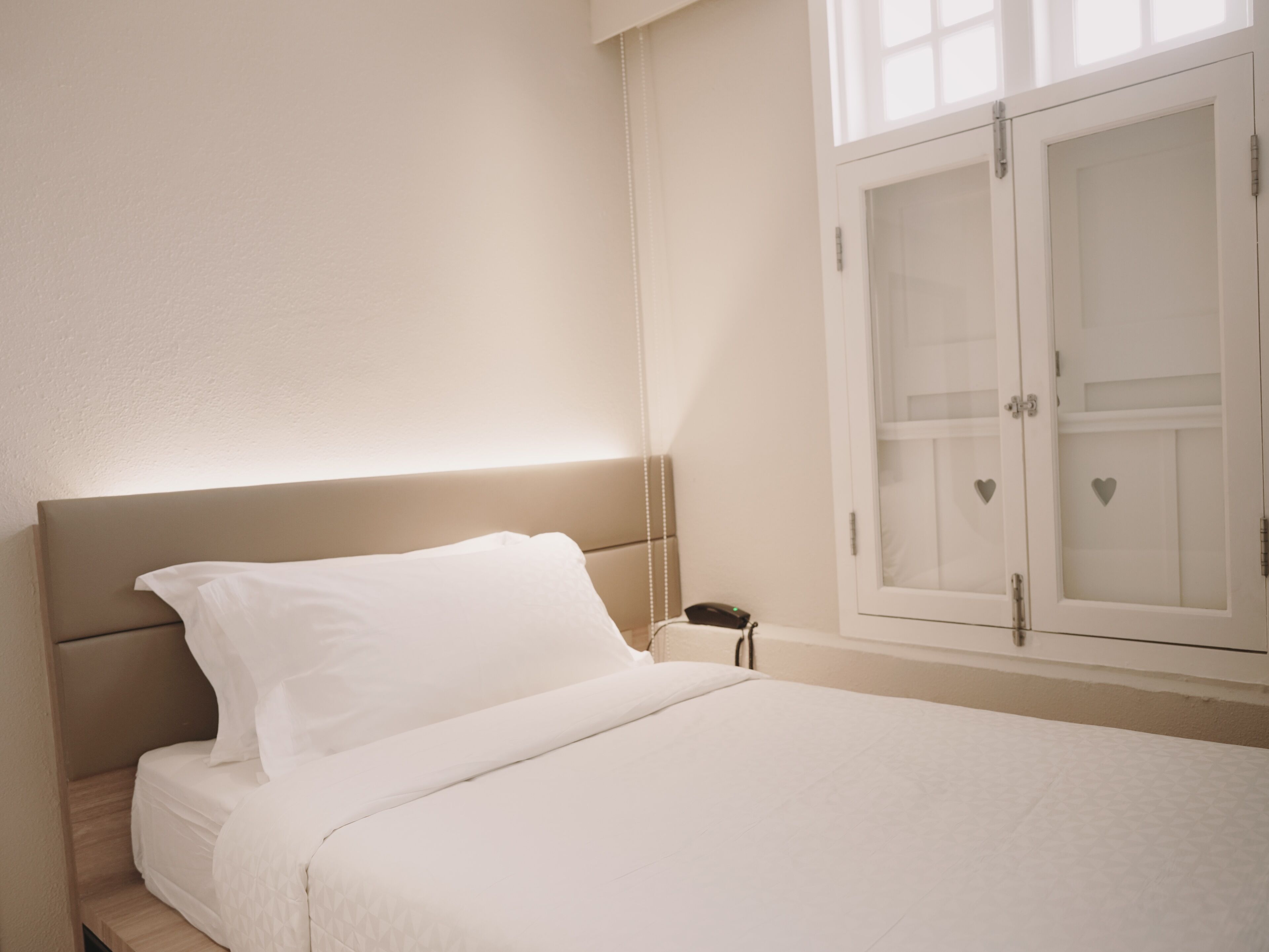 A bedroom with a bed, a bedside table, and a wardrobe with glass doors.