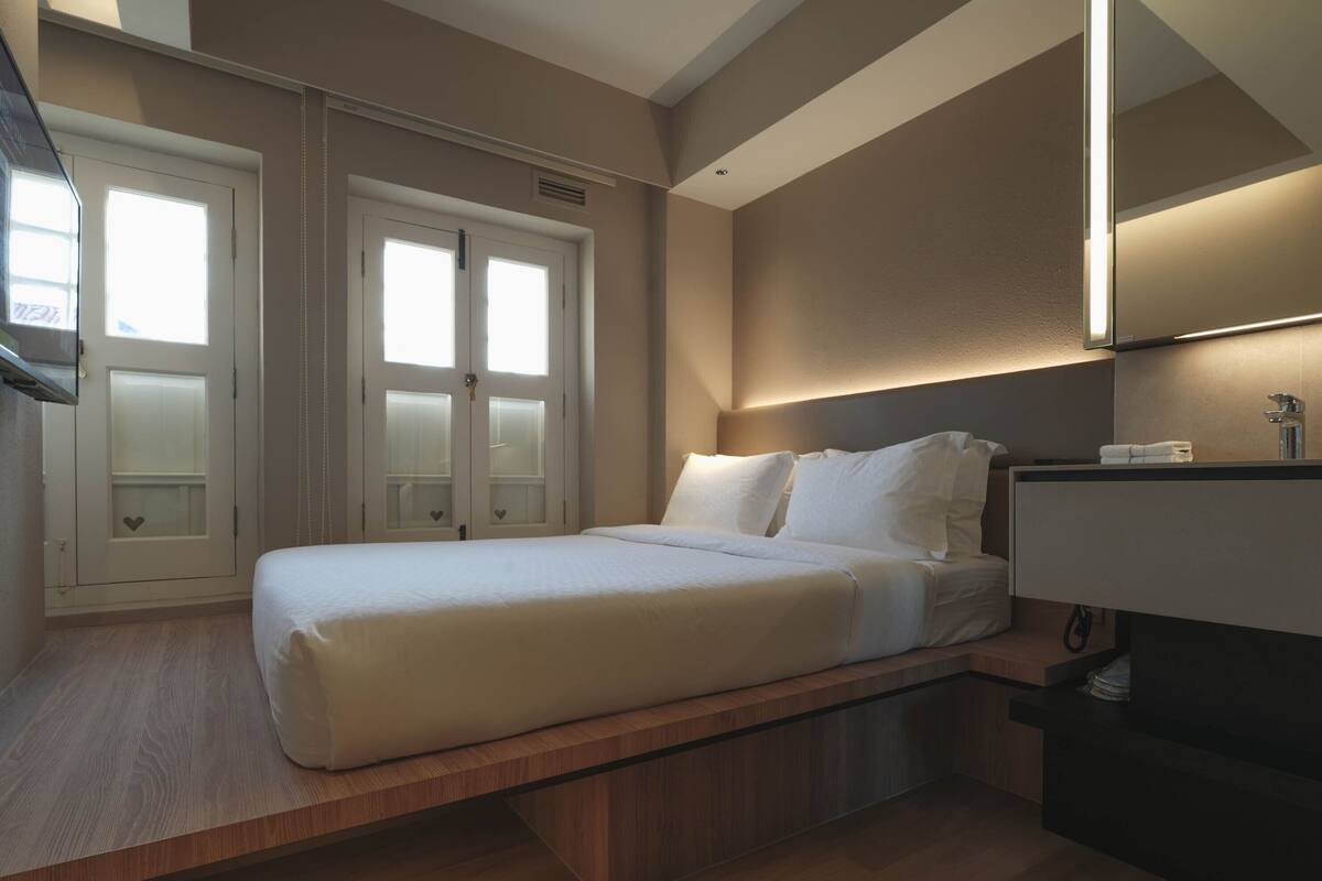 A bedroom with a bed, a bedside table, a mirror, and a wardrobe with frosted glass doors.