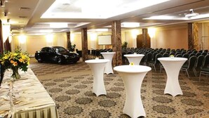 Un salón de conferencias con filas de sillas, un escenario y un coche negro estacionado afuera.