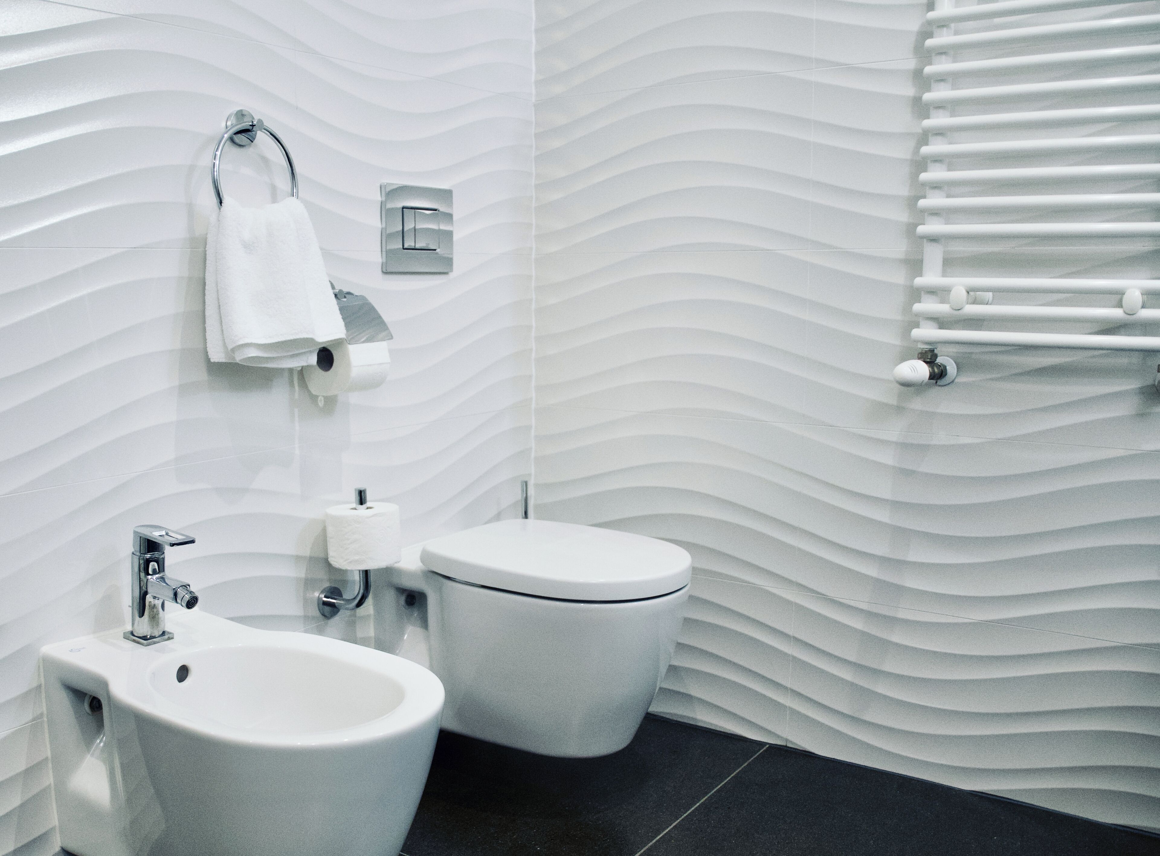 Un baño moderno con bidé, inodoro y un perchero para toallas.