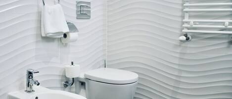 Un baño moderno con bidé, inodoro y un perchero para toallas.