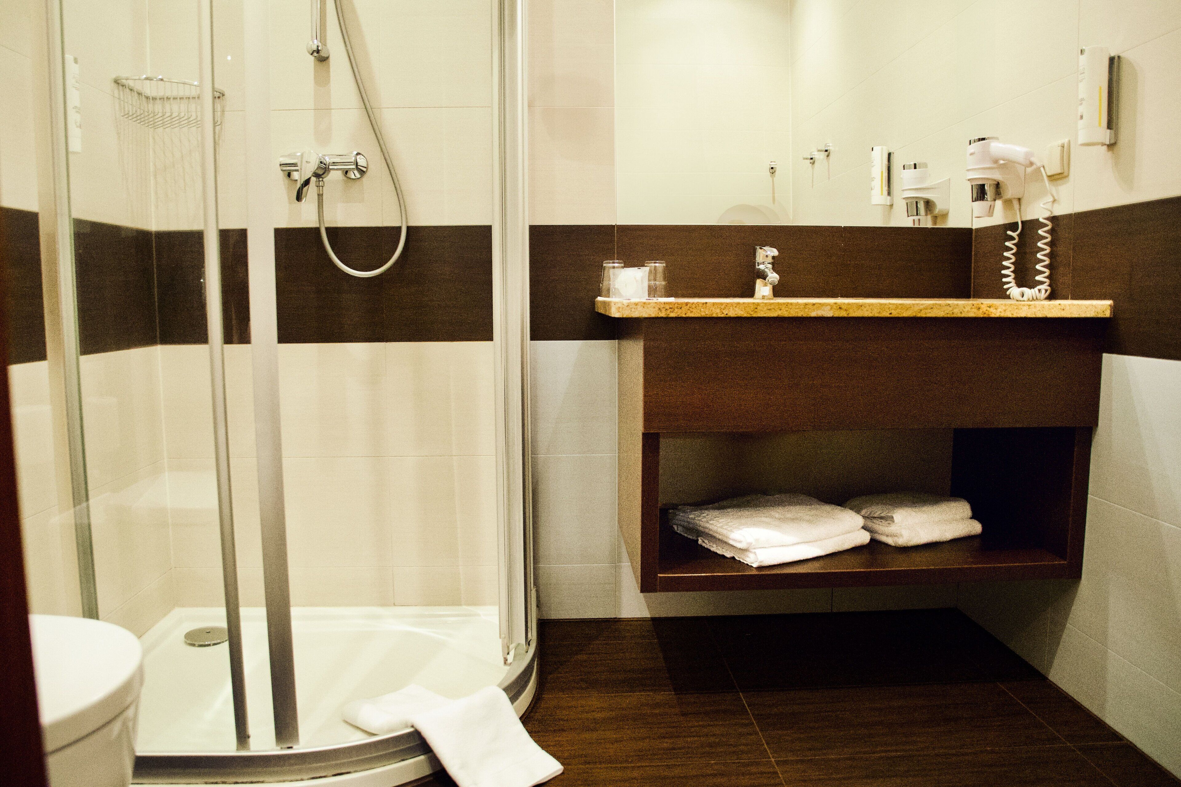 Un baño moderno con ducha envuelta en vidrio, un inodoro y un tocador con toallero.