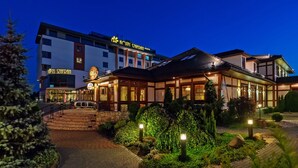 Un hotel de estilo arquitectónico tradicional, con una entrada bien iluminada y un jardín ajardinado.
