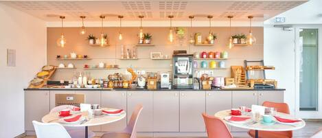 A modern cafe with a central kitchen area, wooden flooring, and round tables with chairs.