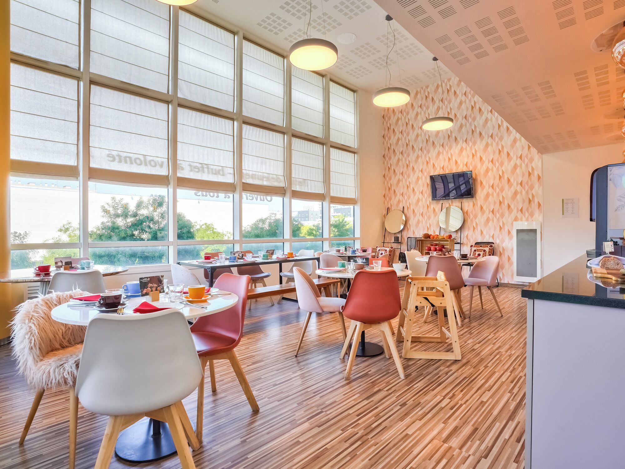 A modern dining area with large windows, wooden flooring, and a variety of seating arrangements.