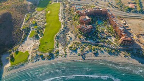 Vue aérienne d’un complexe hôtelier comprenant un terrain de golf, une plage et un grand ensemble d’hôtels.