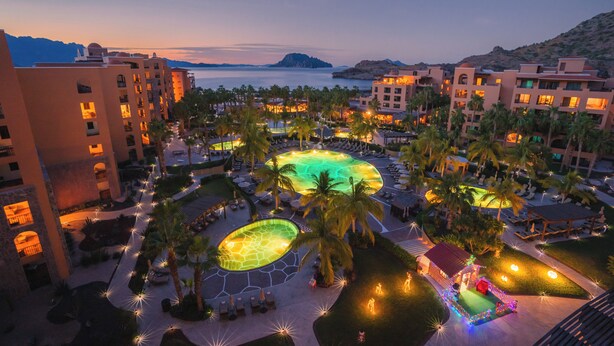 Un complexe hôtelier doté de plusieurs piscines, de palmiers et offrant une vue sur la plage.