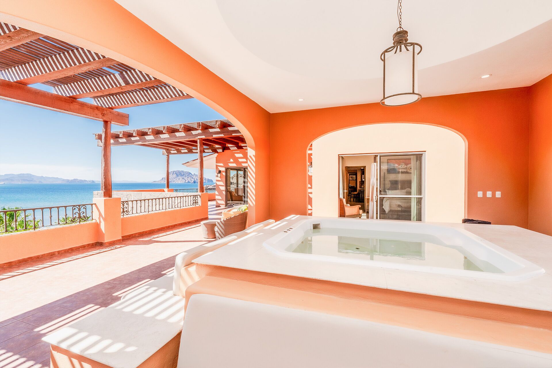 Ein Zimmer mit einer großen Badewanne, einer Pergola mit Meerblick und einer Glastür zum Essbereich.