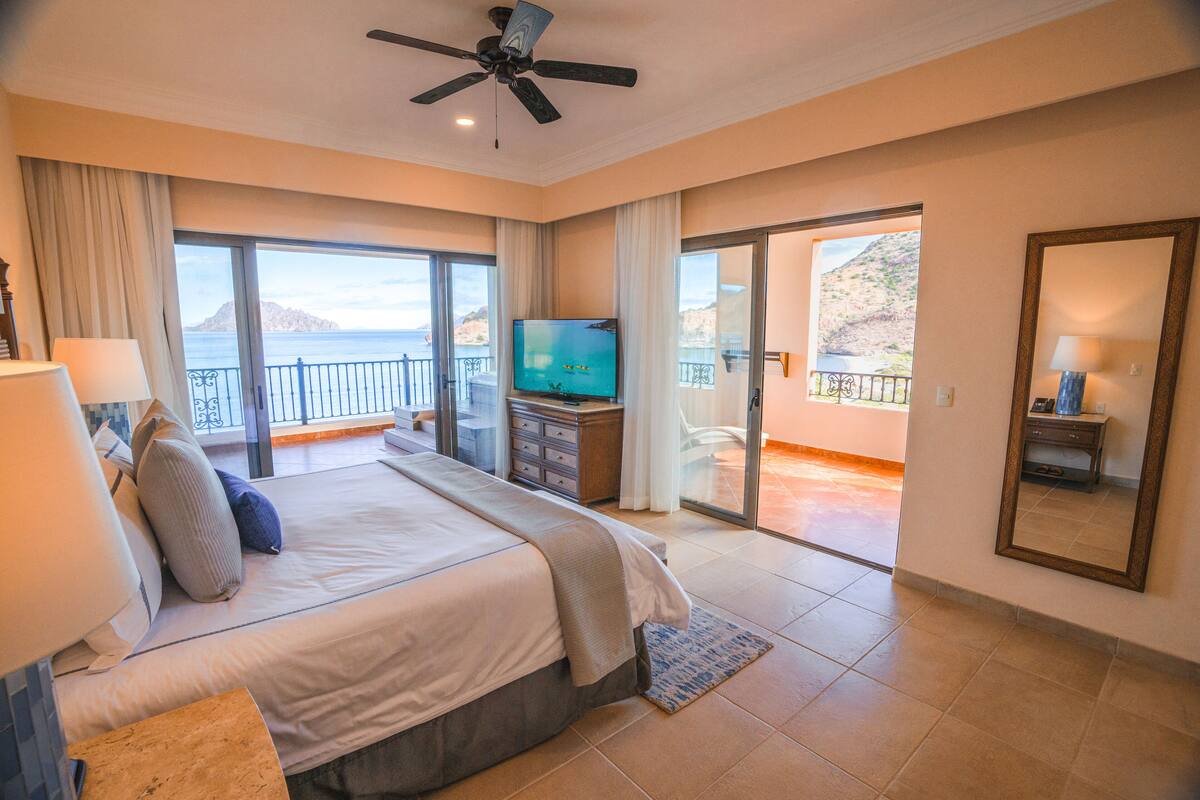 Ein geräumiges Schlafzimmer mit einem großen Bett, einem Fernseher und einem Balkon mit schöner Aussicht.