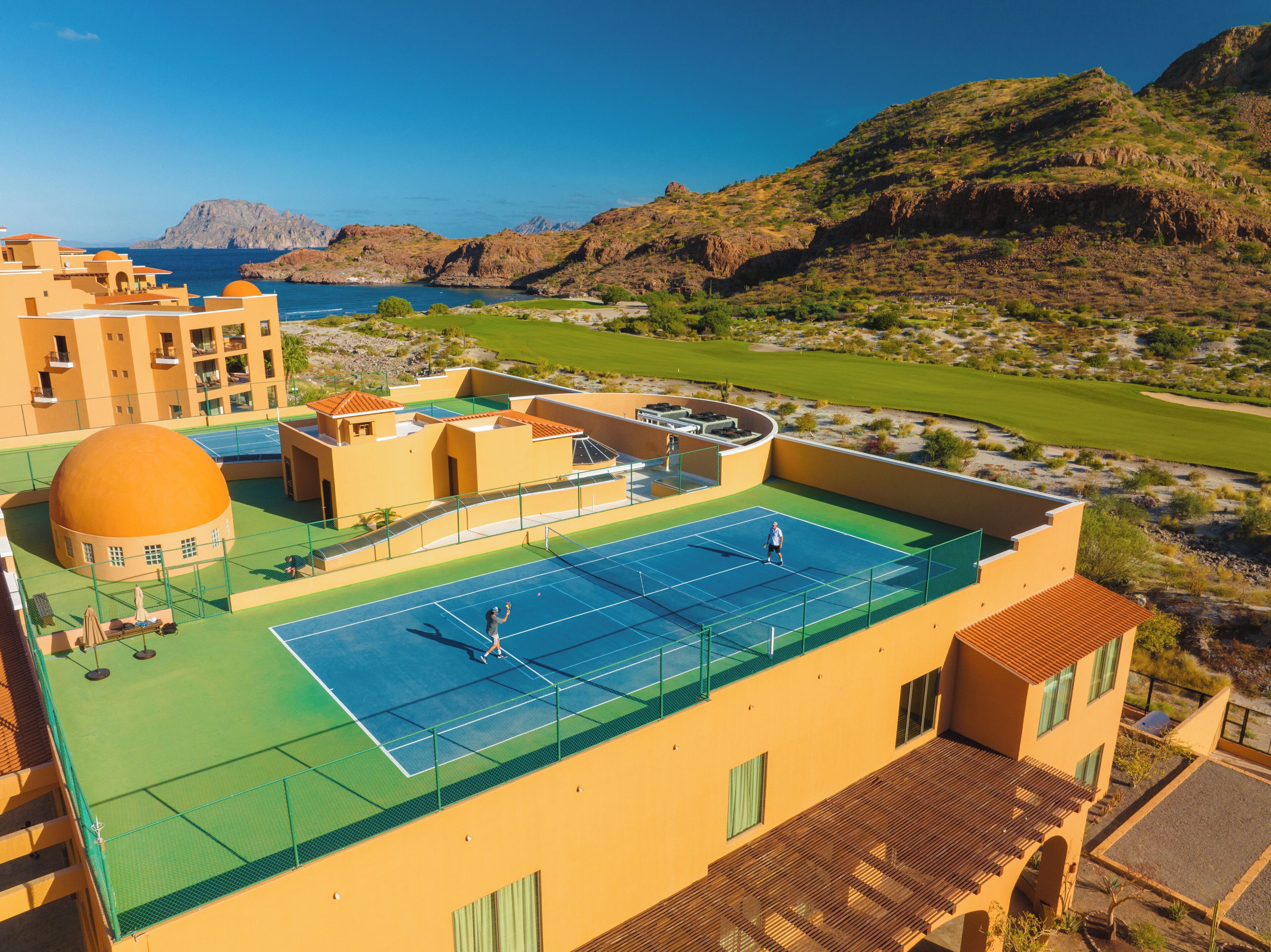 A rooftop tennis court with a view of the surrounding landscape.