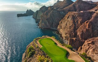 Un campo de golf con vistas despejadas a los acantilados y al océano circundantes.