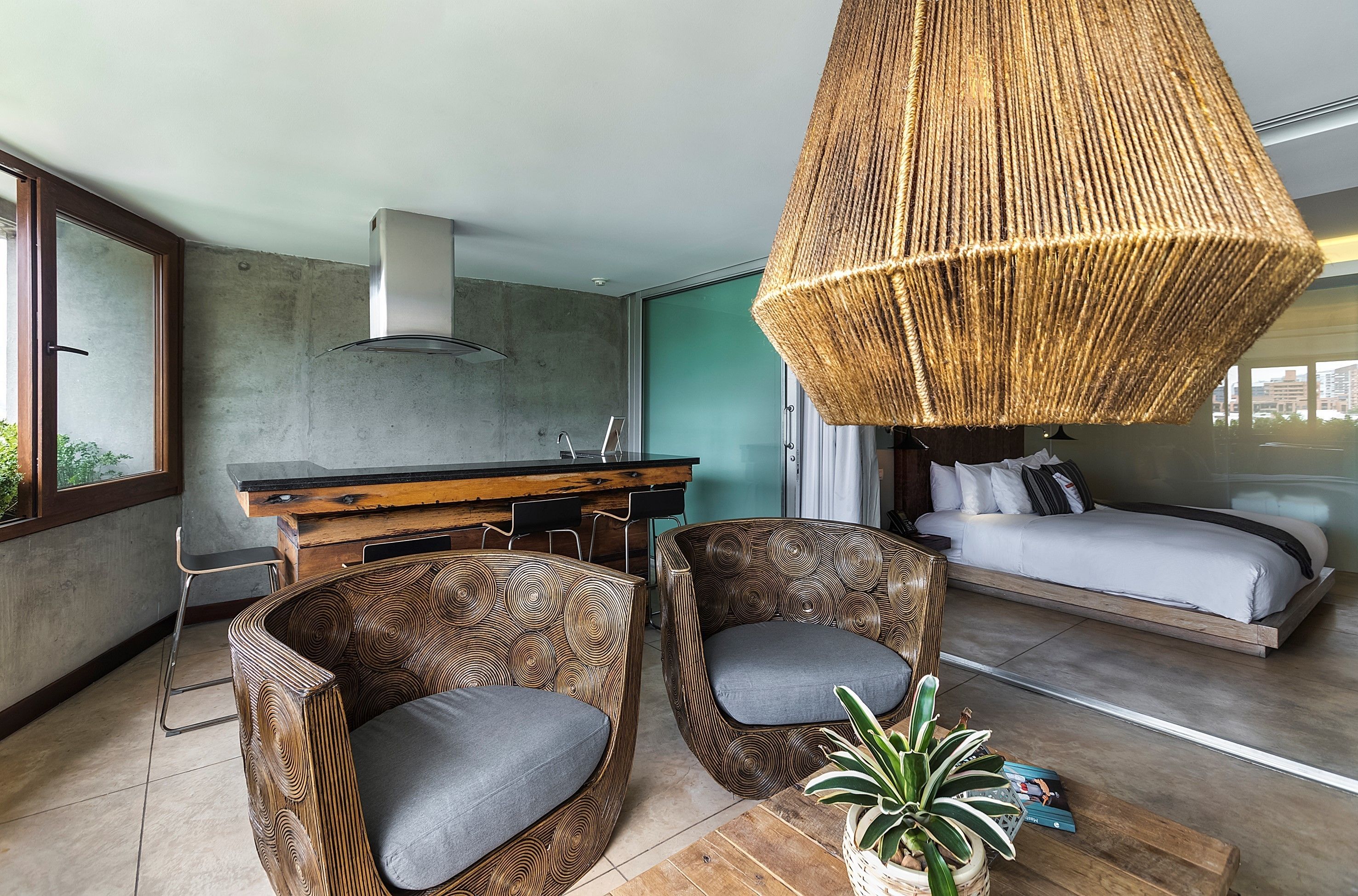 A modern living room with a sofa, a dining area with a bar, and a bed.
