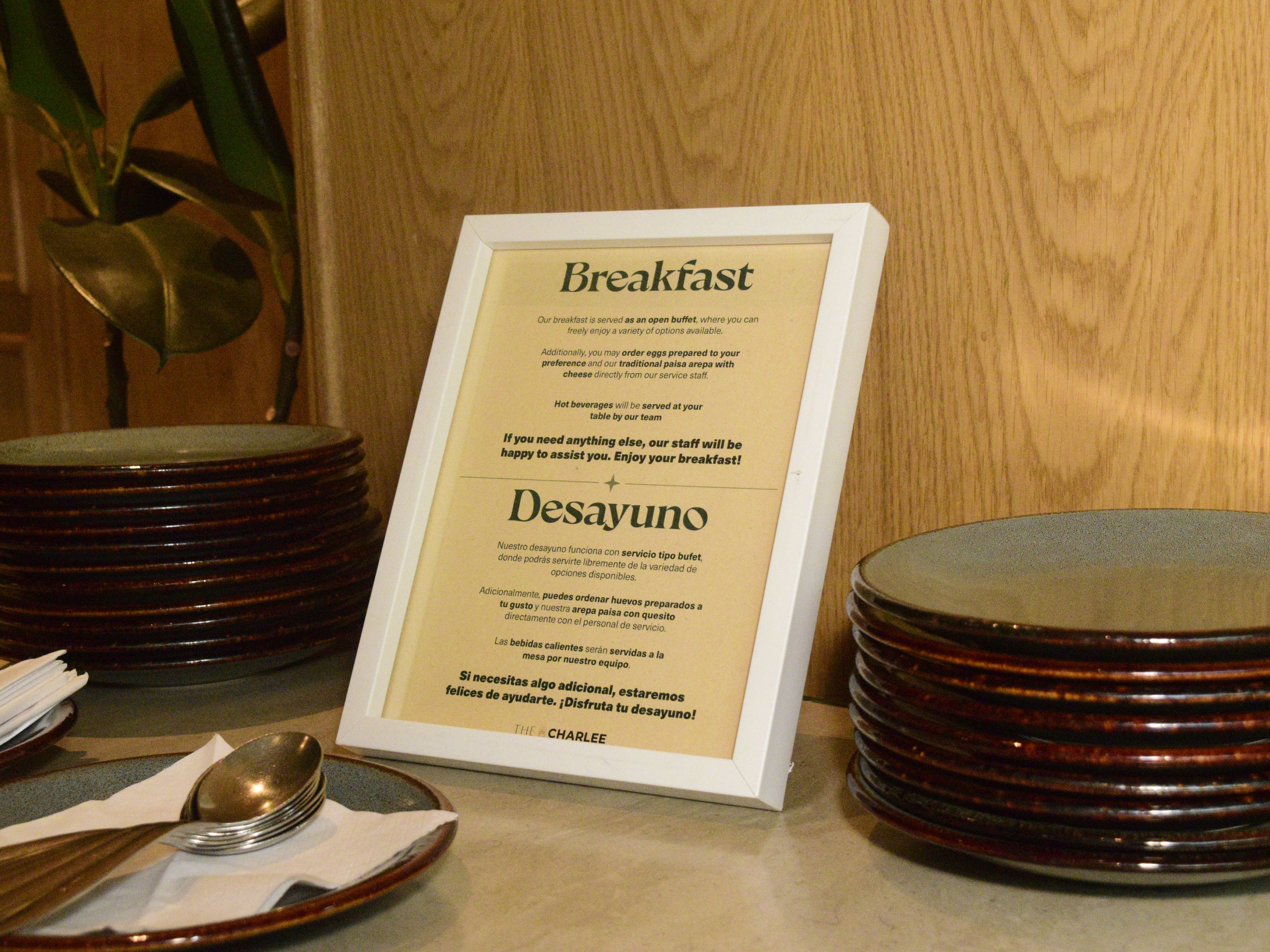 Une affiche présentant le menu du petit-déjeuner, posée sur une table avec des assiettes et des couverts.