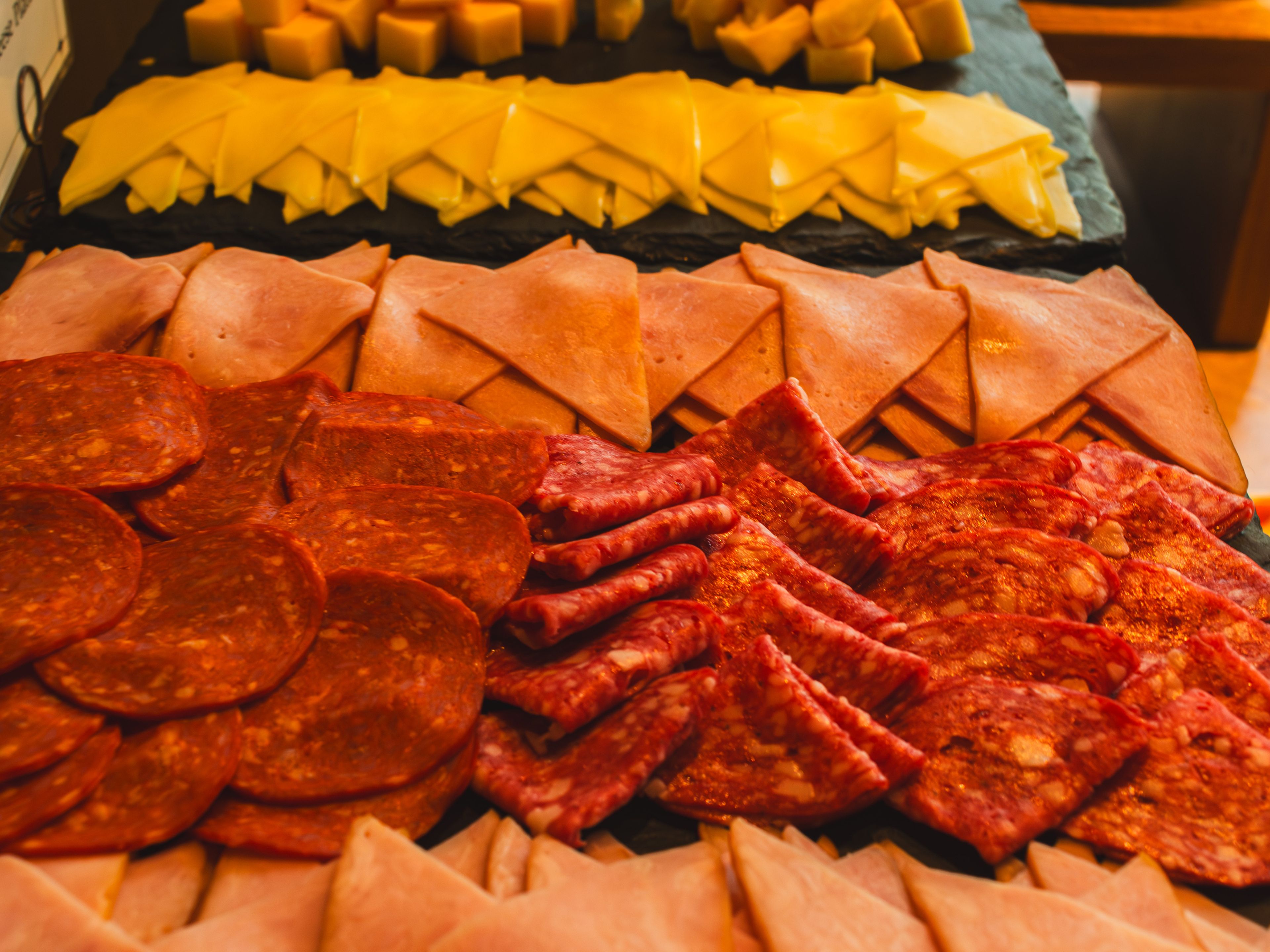 Diversas rebanadas de carnes y quesos dispuestos sobre una tabla de madera.