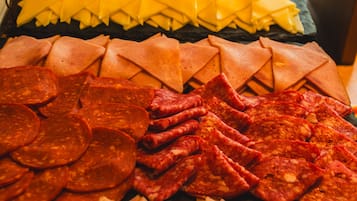 Diversas rebanadas de carnes y quesos dispuestos sobre una tabla de madera.