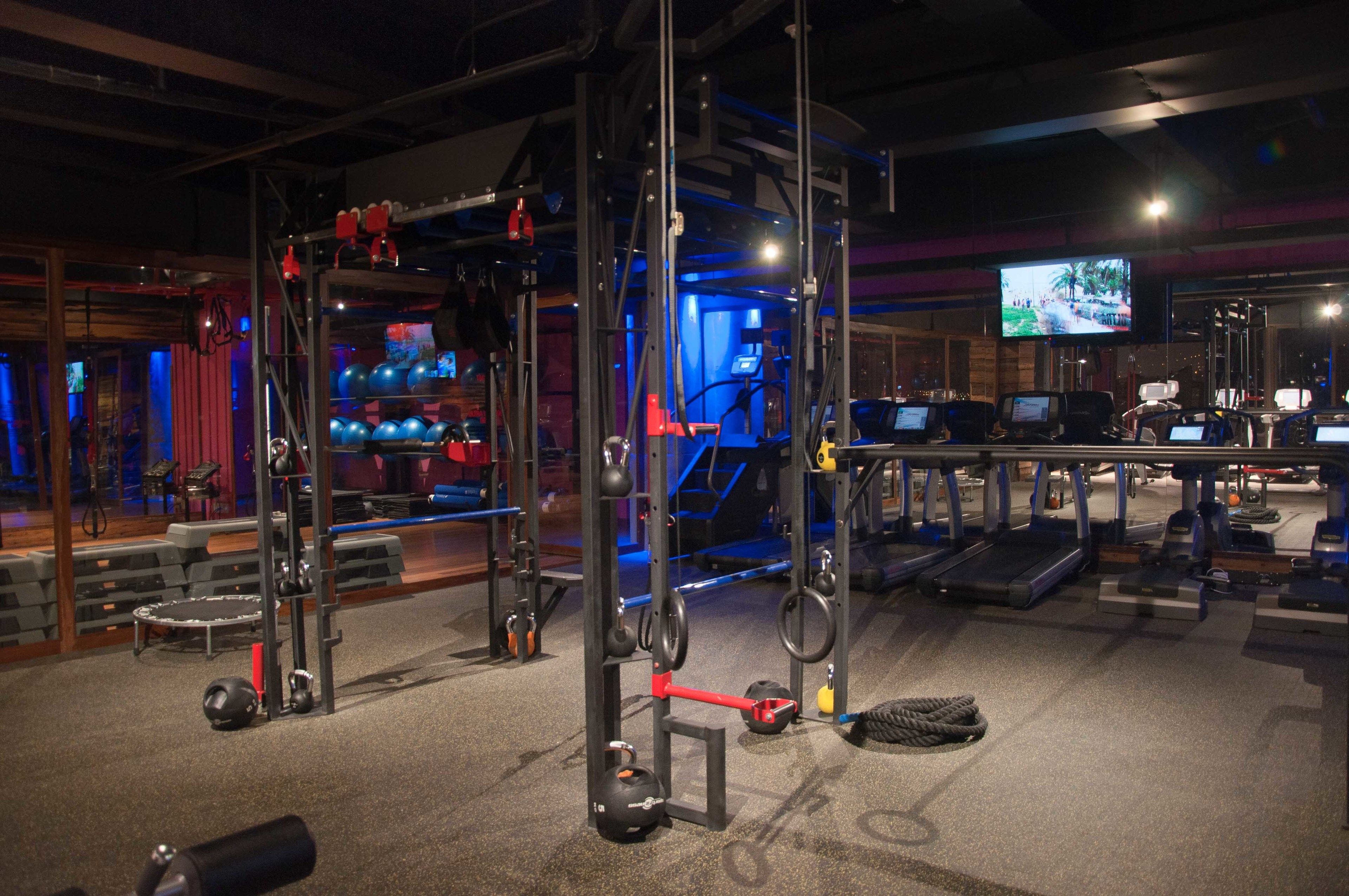 A gym with various exercise equipment, including treadmills, weight machines, and a climbing wall.