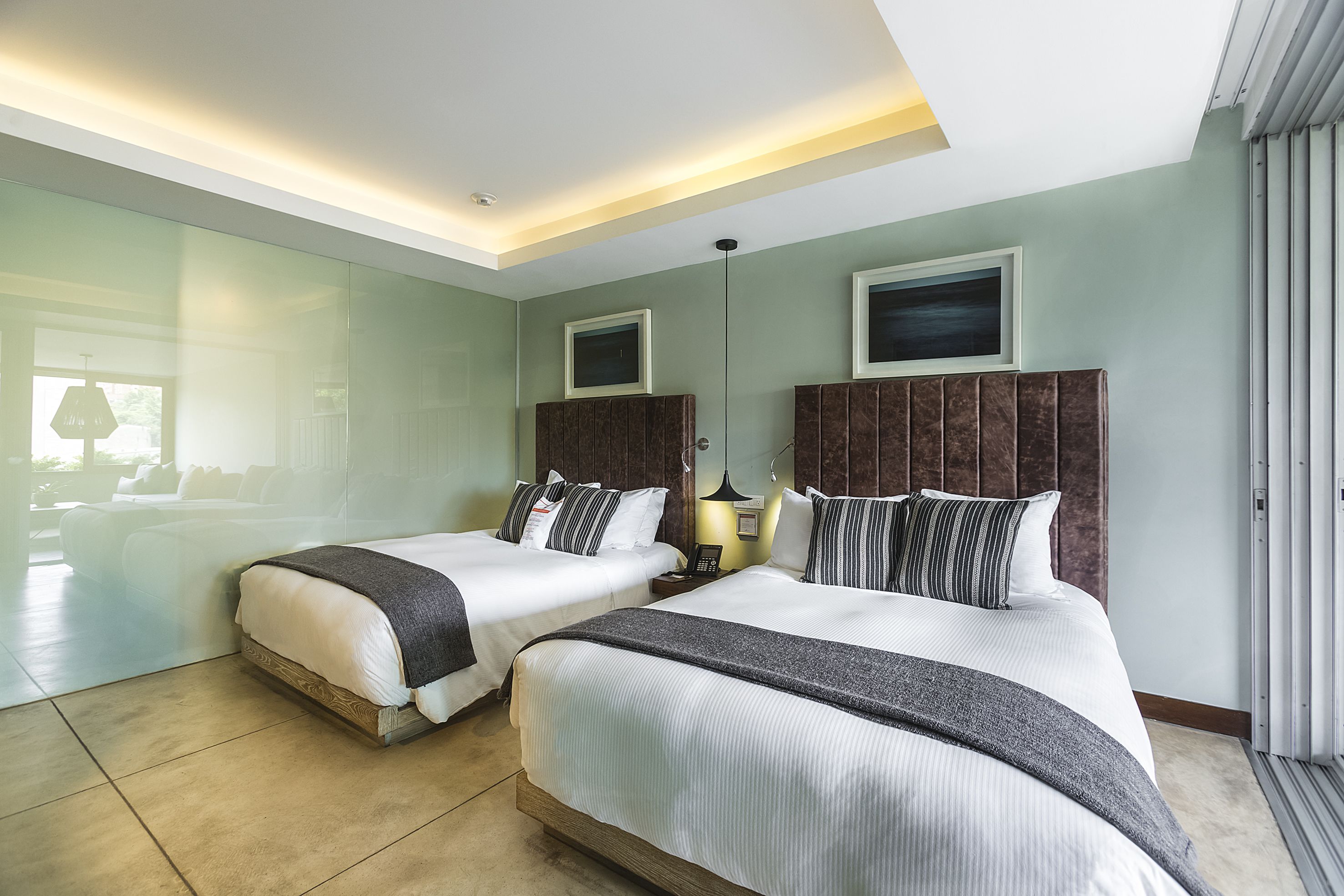 Ett modernt hotellrum med två sängar, ett stort fönster och utsikt över omgivningarna.