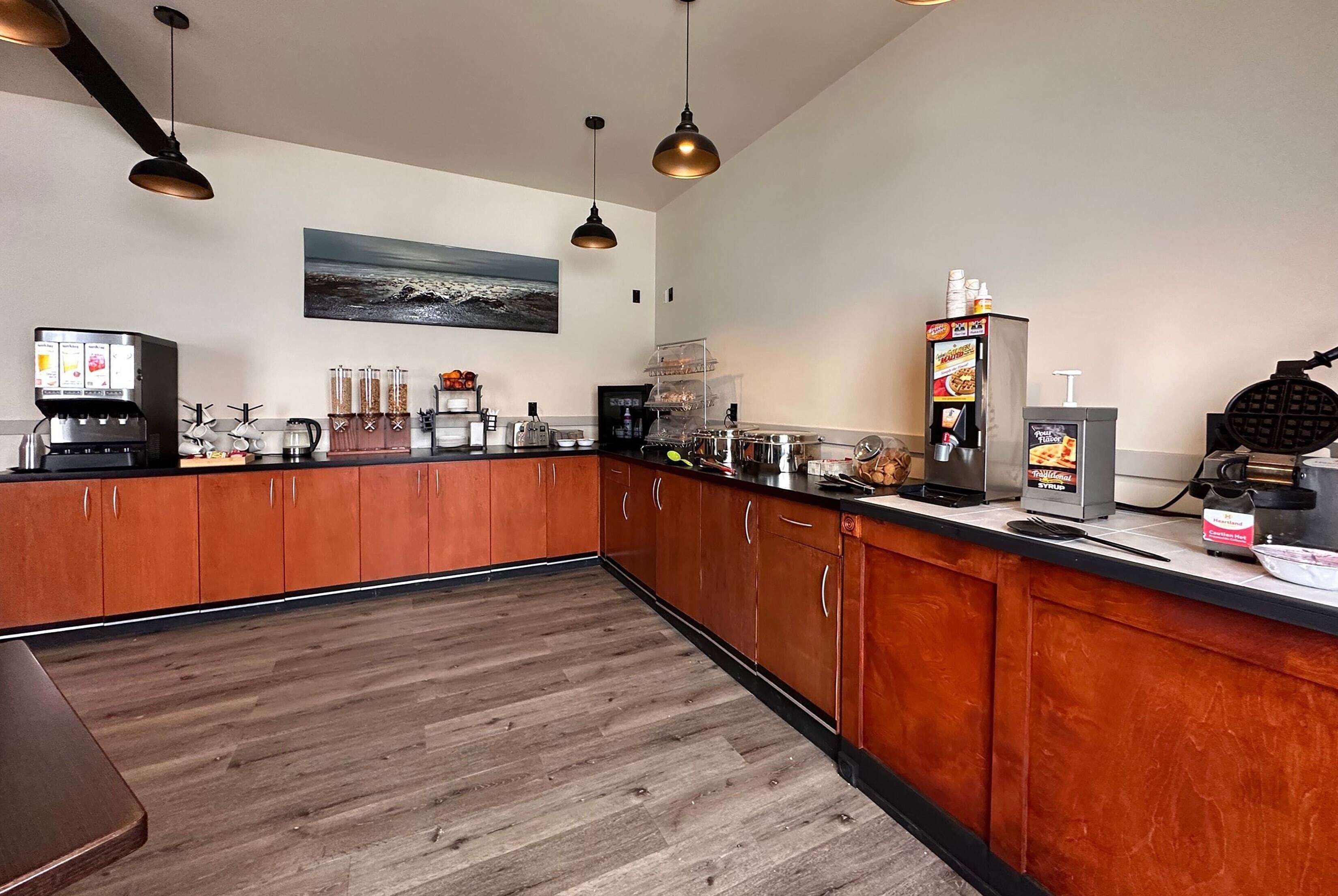 Una cucina moderna con mobili in legno, una macchina per il caffè, una piastra per waffle e un distributore automatico di caffè.
