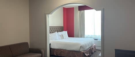 Habitación de hotel con cama, sofá, mesa y vistas al exterior.