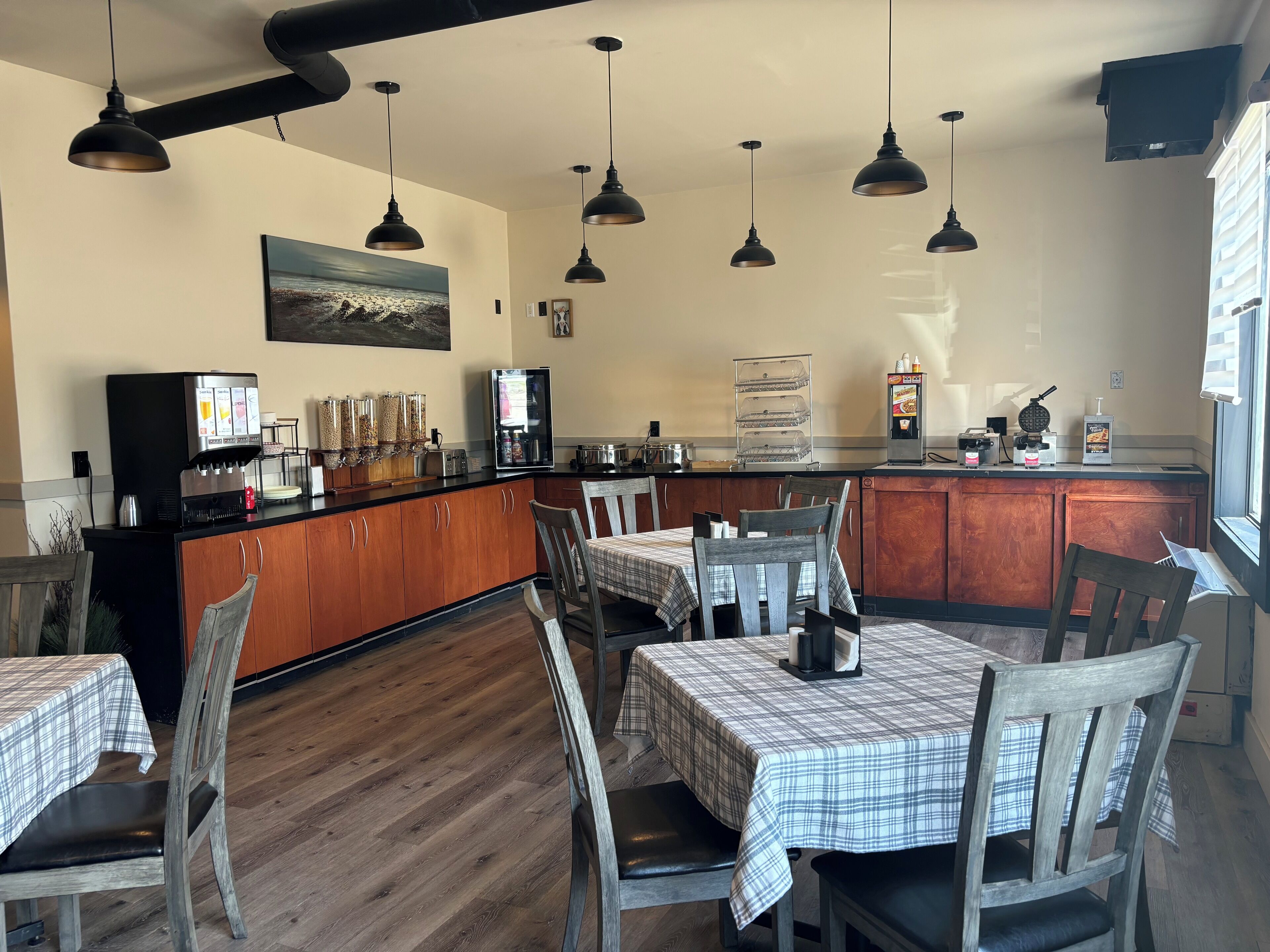 A restaurant with wooden tables and chairs, a coffee machine, and a refrigerator.