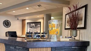 A reception area with a stone counter, a clock, and a large decorative piece on the wall. - Ramada by Wyndham Estevan (Estevan)