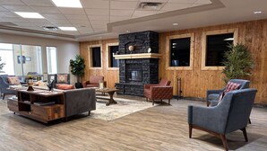 A modern lobby with a stone fireplace, wooden paneling, and comfortable seating. - Ramada by Wyndham Estevan (Estevan)