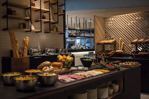 A buffet with various food items and a bar area in the background. - Courtyard by Marriott Paris Arcueil (Arcueil)