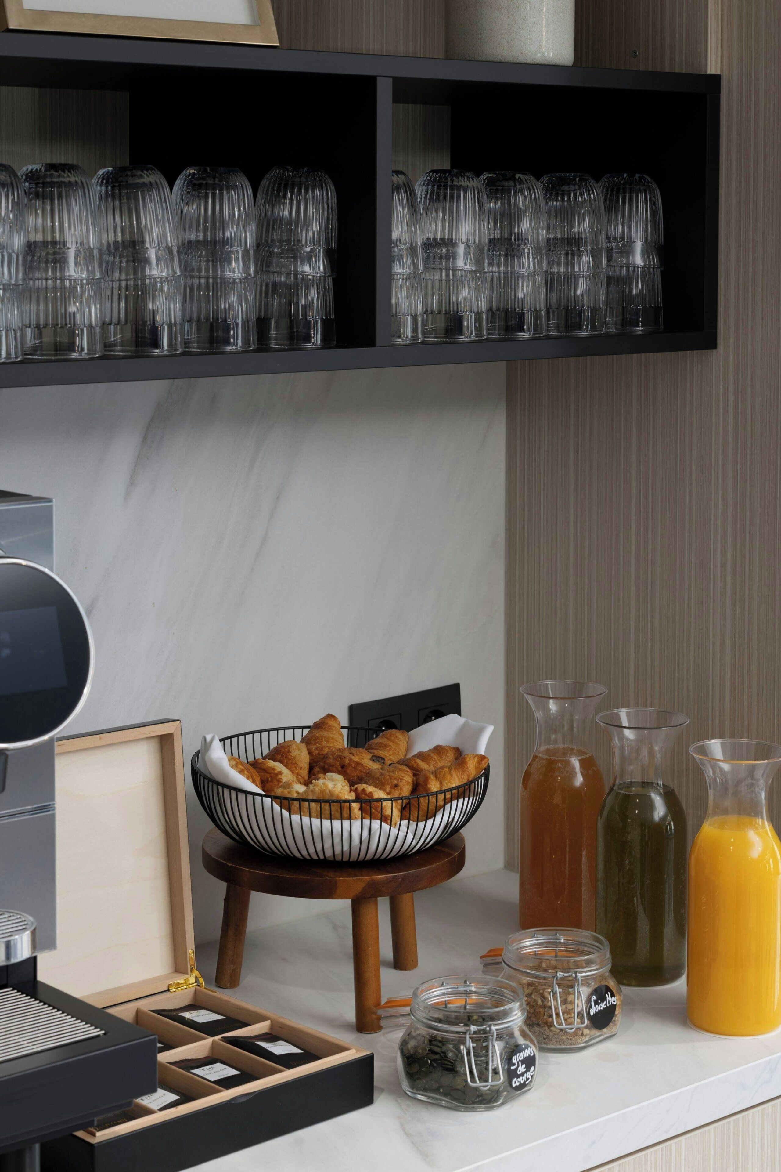 A breakfast setup with croissants, a coffee machine, and various beverages.