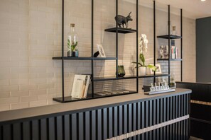 A reception desk with a modern design, featuring a black and white color scheme, and shelves displaying various decorative items and a sign for 'ELITE MEMBERS'. - Courtyard by Marriott Paris Arcueil (Arcueil)