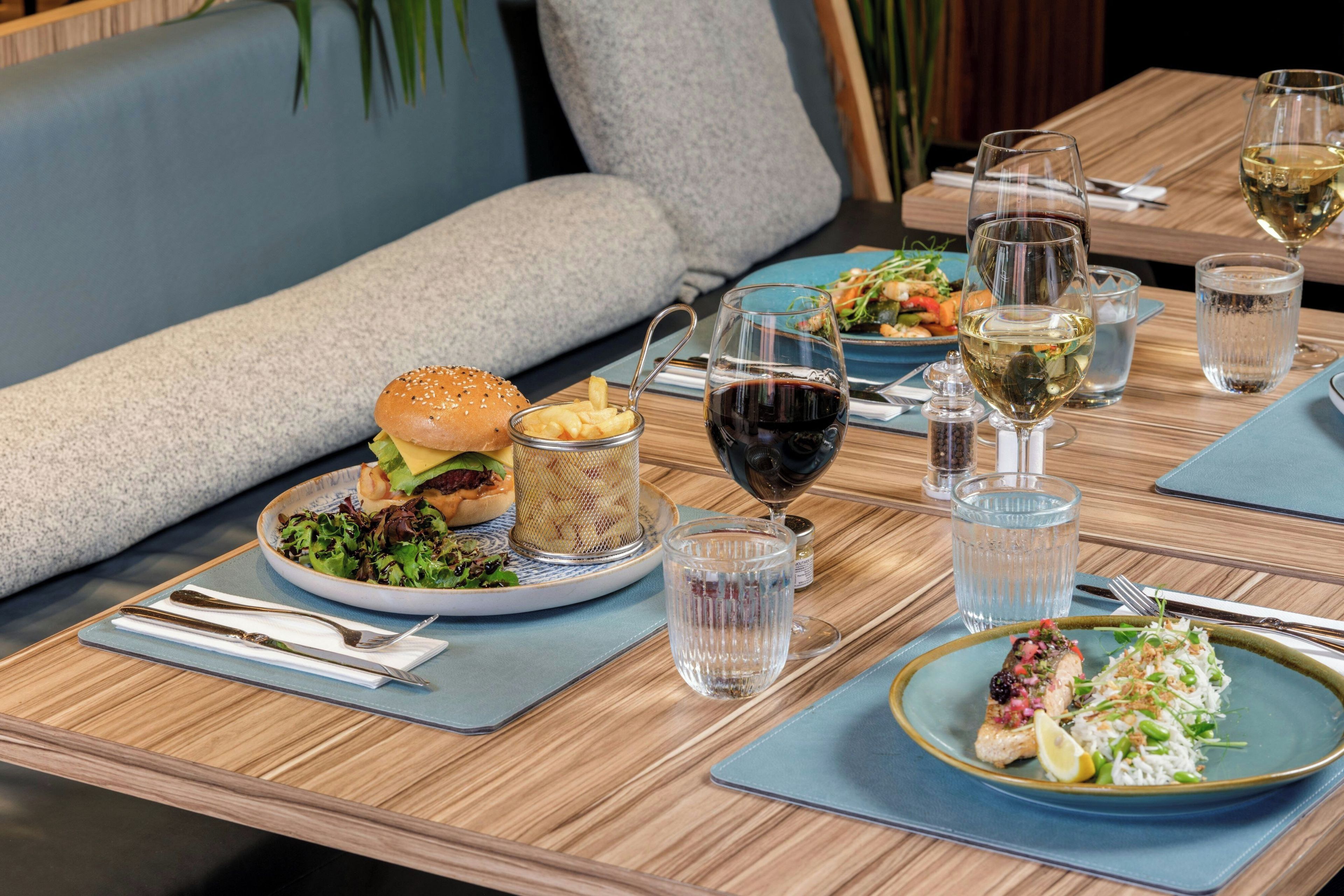 A dining table set with plates of food, glasses of wine, and a variety of cutlery.