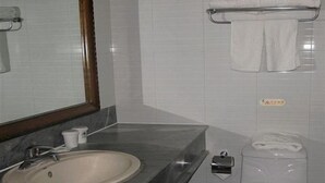 A bathroom with a sink, mirror, toilet, and towel rack.