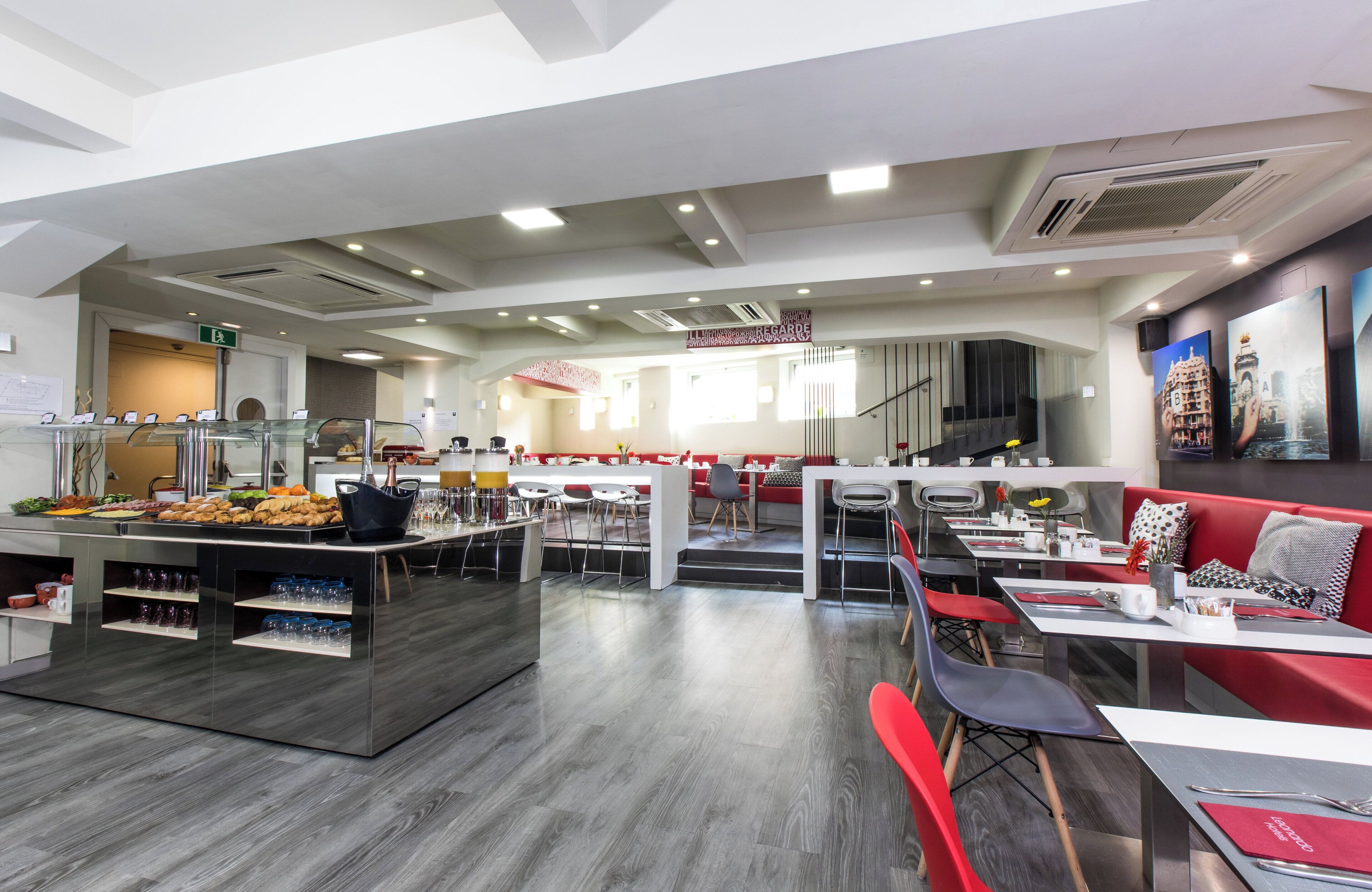 Un restaurant moderne doté d’un espace buffet, de tables et de chaises aux couleurs rouge et blanche, et d’un escalier menant à un niveau supérieur.
