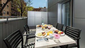 A table set for breakfast with plates of food, a bottle, and a flower.