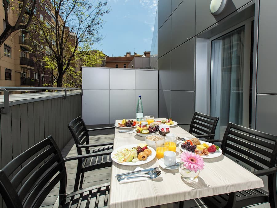A table set for breakfast with plates of food, a bottle, and a flower.