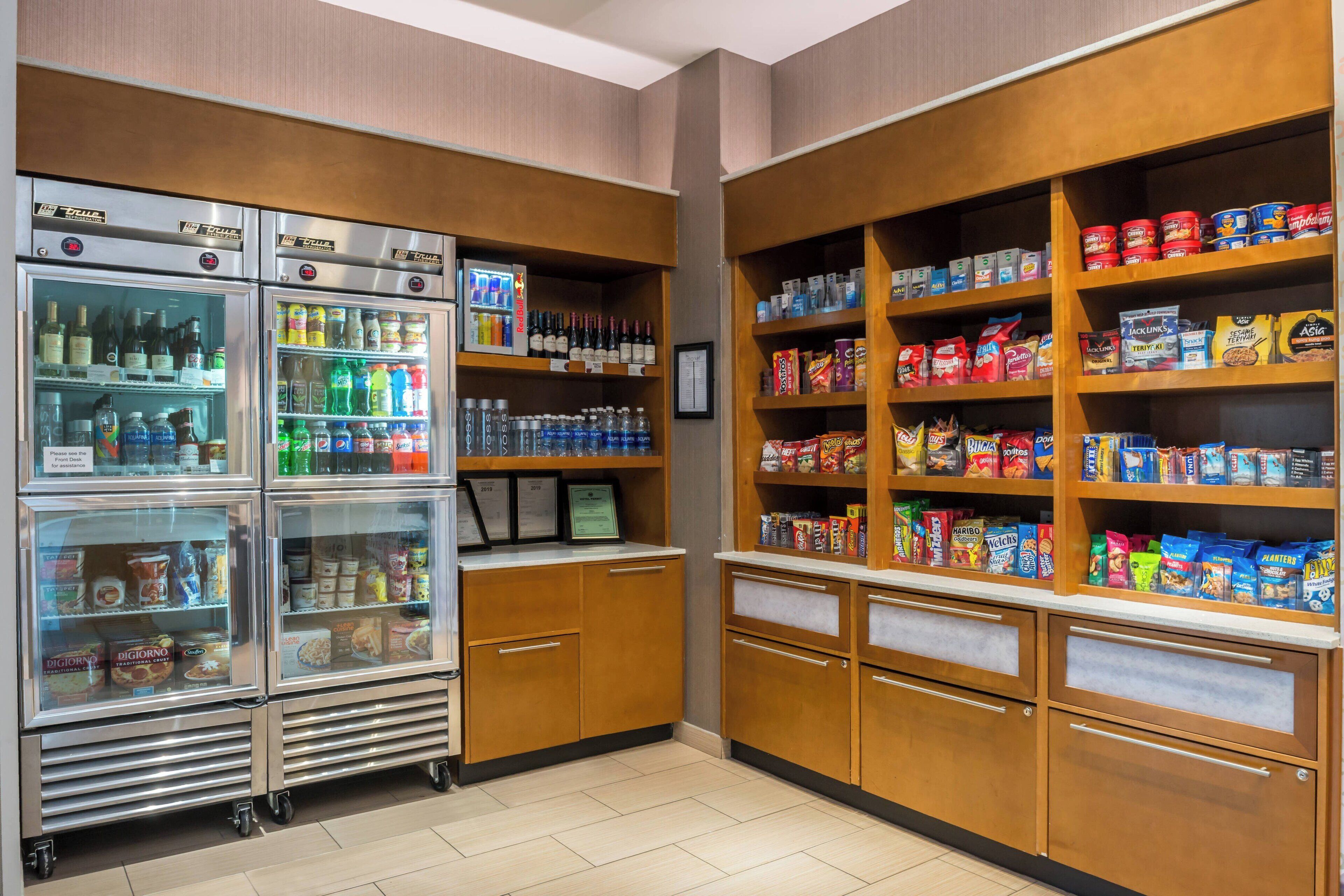 A self-service food area with refrigerated beverage dispensers, snack shelves, and refrigerated food items.