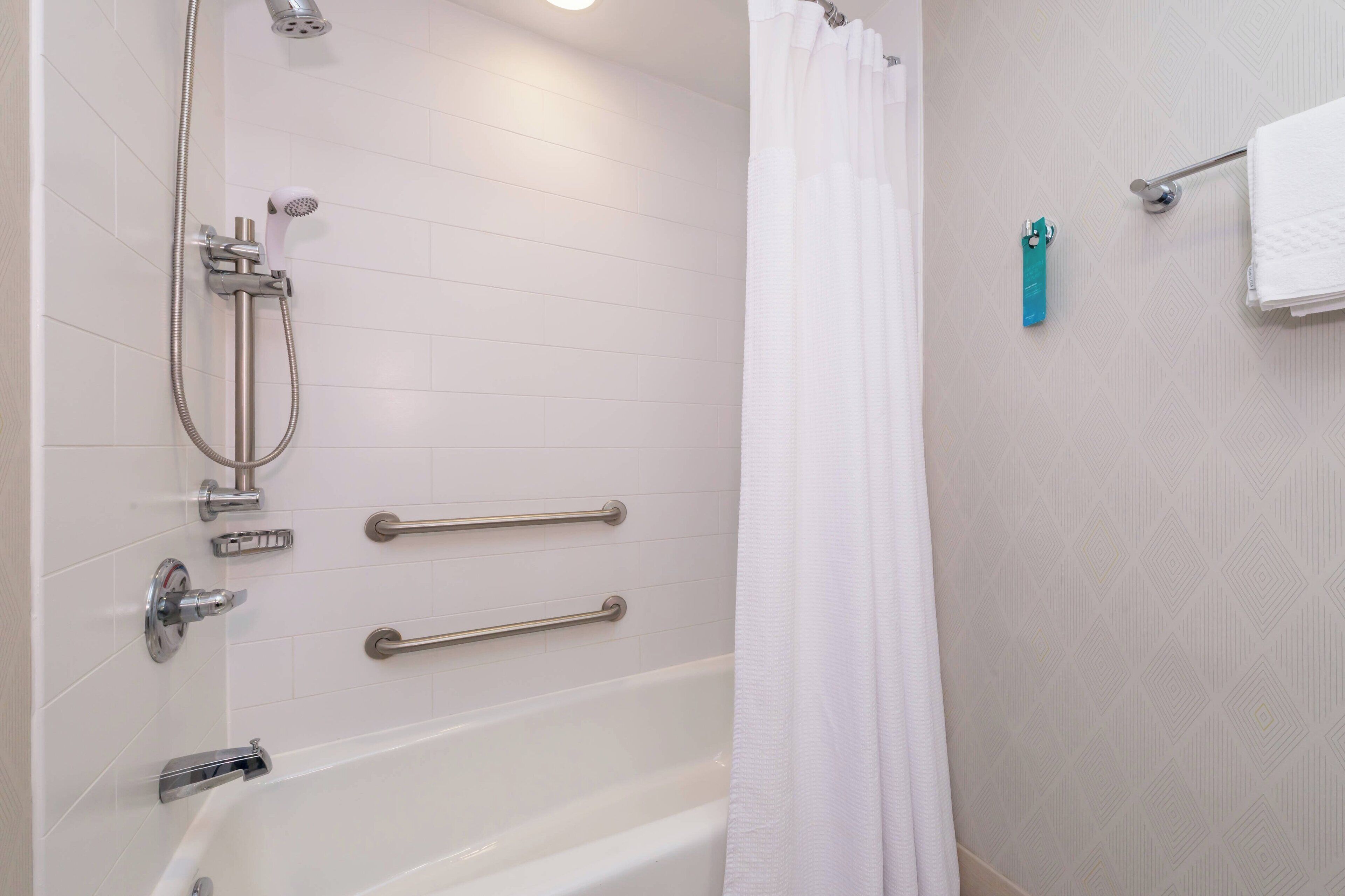 Une salle de bain moderne équipée d’une baignoire, d’une douche et de barres d’appui.