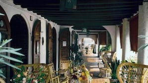 A covered outdoor area with wooden furniture and arches. - Hotel Arnaldo Aquila d'Oro (Rubiera)