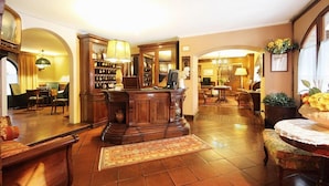 A spacious living room with a wooden coffee table, a bookshelf, and a large mirror. - Hotel Arnaldo Aquila d'Oro (Rubiera)